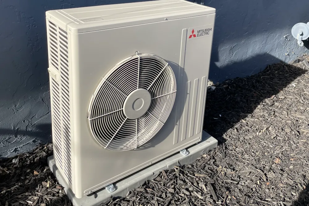 Heat pump next to house wall.